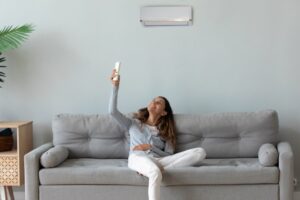 woman-sits-on-sofa-changes-mini-split-with-remote